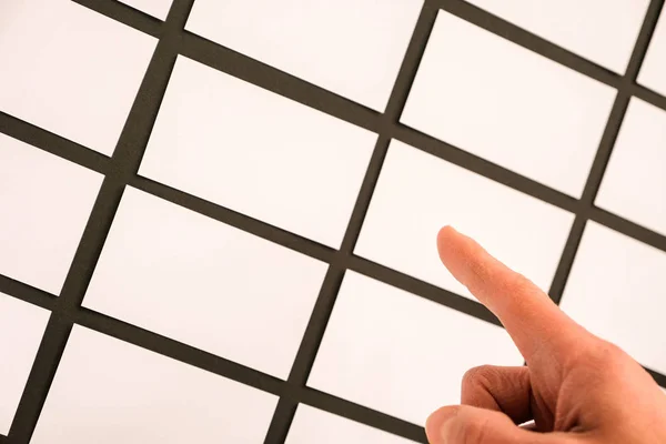 Many business cards on the desk top and a human hand holding an empty business card; close-up shot