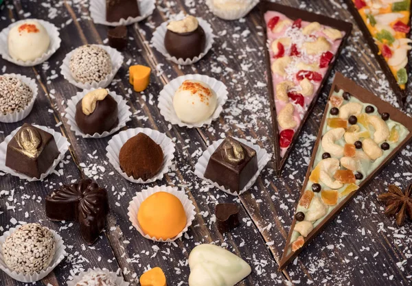 Delicious truffles and slices of chocolate pizza on wooden background