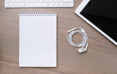 Çalışma alanı arka plan: bir tablet, bir not defteri ve ahşap masa üzerinde kulaklık