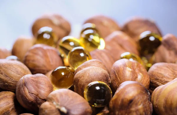 Hazelnuts and capsules with vitamin, wooden background