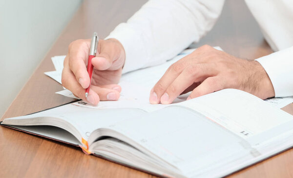 Unrecognizable businessman taking notes in dairy, closeup shot