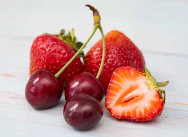 木制背景上的新鲜樱桃和草莓 — 图库照片