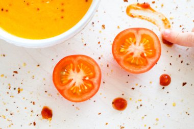 Biber biber ile bir kase sıcak krem çorbası. Bir çocuk domates sosu ile çizer. Beyaz arka plan.