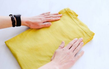 Woman tidy folds male t-shirt on a white background