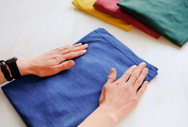 Woman tidy folds male t-shirt on a white background