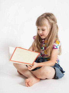A charming little girl reads a book clipart