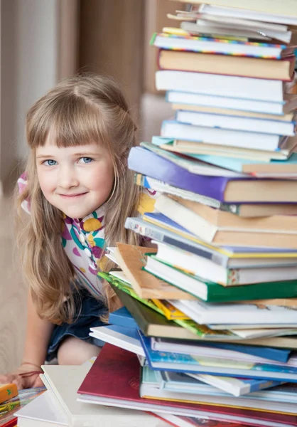 一个迷人的小女孩从一叠书后面偷看. — 图库照片