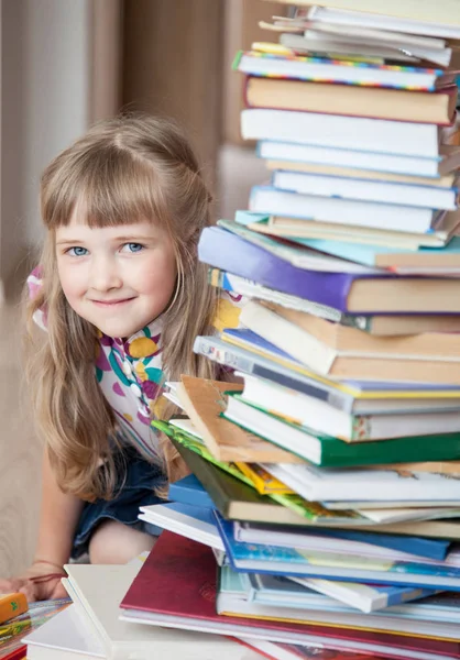 A charming little girl peeks out from behind a stack of books. Royalty Free Stock Images