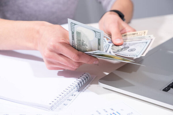 Руки женщины держат доллары
