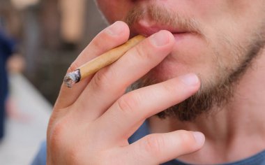 Beyaz adam sigara içiyor.