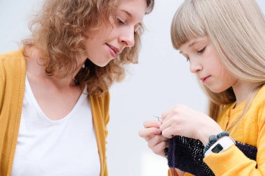 Anne kızına örgü örmeyi öğretiyor.