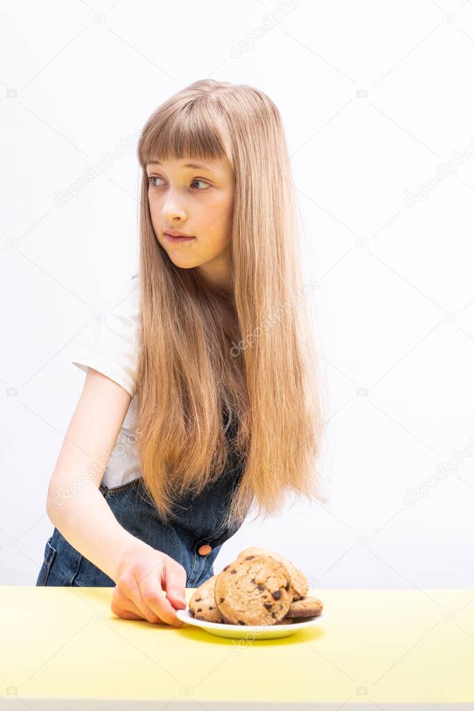 Cute girl wants cookies and doubts her choice; neutral background