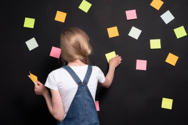 Bir kız görevler hakkında düşünüyor; siyah arkaplanda bir sürü etiket