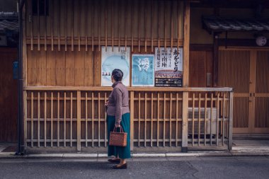 Kyoto, Japan - November 19, 2018: A senior Japanese woman looking at a poster outside of a theater house.