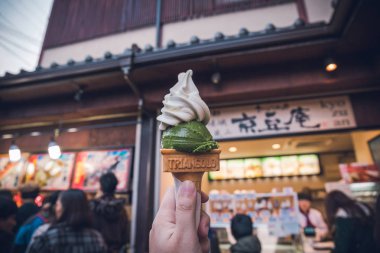 Kyoto, Japonya - 23 Kasım 2018: Arashiyama'da bulunan bir Japon tatlı dükkanında kavrulmuş çay ve matcha flavor dondurma tutan adam eli