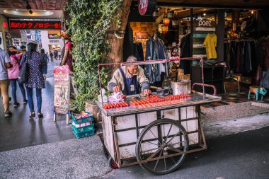 Taipei, Tayvan - 23 Mayıs 2018: Taipei'nin Wanhua Semtindeki Ximending'de çubuklar üzerinde tatlı sırlı kırmızı şekerleme meyve şekeri satan Tayvanlı bir sokak gıda satıcısı.