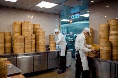 Taipei, Tayvan - 23 Mayıs 2018: Mutfak personeli, bambu buharlı sepetleri üst üste istiflemeye başladı ve Taipei, Tayvan'ın Din Tai Fung restoranında buharlı köfteile servis edilemeye hazır.
