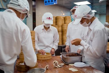 Taipei, Tayvan - 23 Mayıs 2018: Din Tai Fung'Un Taipei 101 restoranında açık mutfakta ünlü çorba köftesi yapmakla meşgul olan bir grup usta şef