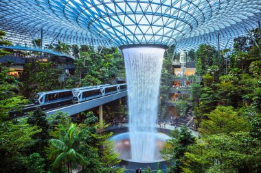 Singapore - July 24, 2019: The world's tallest indoor waterfall, named the Rain Vortex, which is surrounded by a terraced forest setting at Jewel Changi Airport, Singapore. clipart