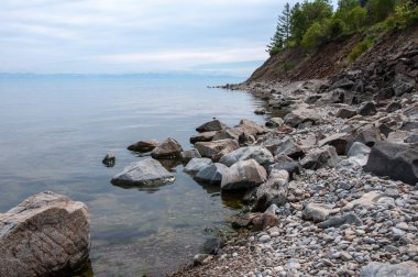 Baykal Gölü kıyısında kayalar ve dağ ufukta