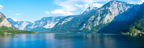 Panoramic views of the Alpine lake and the town of Hallstatt, surrounded by mountains.