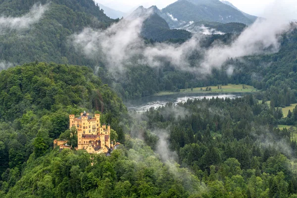 Royal castle bir dağ Gölü kıyısında. Fırtınalı gökyüzü ve sis karşı orman kaplı dağlar.