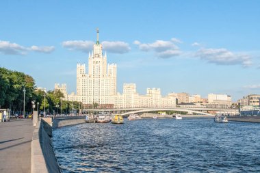 Stalin'in yüksek katlı ve Moskova nehri üzerindeki köprü mavi gökyüzüne ve bulutlar zincirine karşı. Yaz şehir manzara, dalgalı su üzerinde zevk tekneler