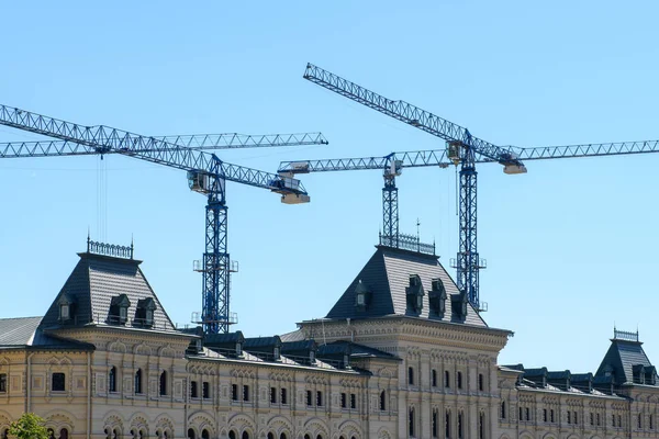 Mavi bir gökyüzüne karşı gotik bir binanın çatısı üzerinde birkaç çalışma kule vinçler