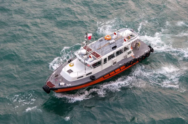 Gök mavisi deniz dalgaları üzerinde beyaz-kırmızı deniz kurtarma botu. Hava görünümü.