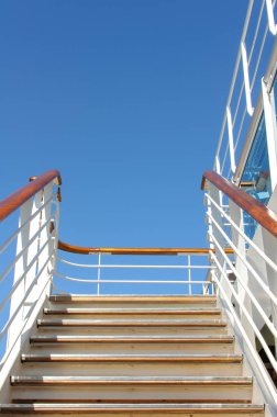 Mavi gökyüzüne karşı bir yolcu gemisinde üst güverteye tırmanmak için korkuluk ile Merdivenler.