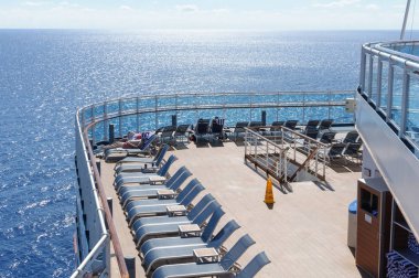 View from the deck of a cruise ship in the ocean. Seating area for passengers, chairs and sun loungers. Sunbathe. clipart
