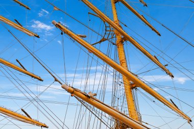 Tahta direkler, yedek yelkenliler ve yelkenliler mavi tropikal gökyüzüne karşı.