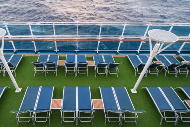 Şezlonglar, korkuluklar ve okyanus manzaralı yolcu gemisinin güvertesi.