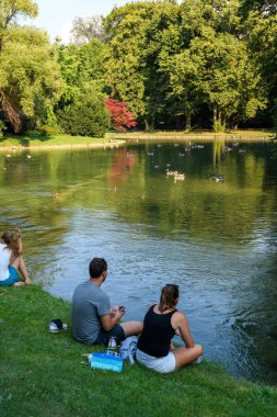 Münih, Almanya - Ağustos 2018: Vatandaşlar gölgeli bir şehir parkında kavurucu güneşin içinde rahatlıyor.