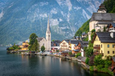 Batan güneşin ışınlarında dağların arka planında bir dağ gölü nün kıyısında dağlık bir Avusturya köyünün görünümü. Hallstatt. Hallstattersee. Avusturya.