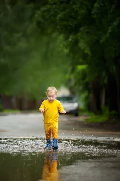 一个小男孩在水坑里跑来跑去 图库照片
