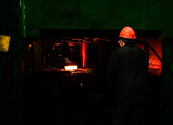 Hot iron in smeltery held by a worker. Iron melting recycling work. Heavy forging steelmaking plant and steelmaking workshop.