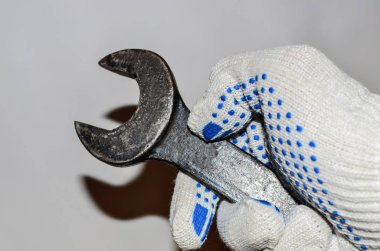 Beyaz duvar arka plan üzerinde beyaz bir eldiven bir adamın elinde somun anahtarı... İnşaat araçları. Tesisatçı