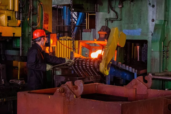 Hot iron in smeltery held by a worker. High precision hot forging product, automotive part production by hot forging process, automatice line hot forging. iron melting recycling work.