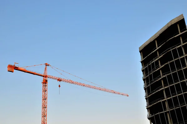 Industrial construction cranes and building silhouettes over sun at sunrise. Abstract Industrial background  of blue sky and clouds