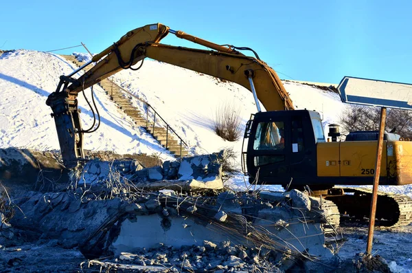 Excavator hydraulic crushes concrete slabs. Heavy construction equipment. Hydraulic breaker piles concrete and reinforcement pile elements into the ground and processes high-strength material