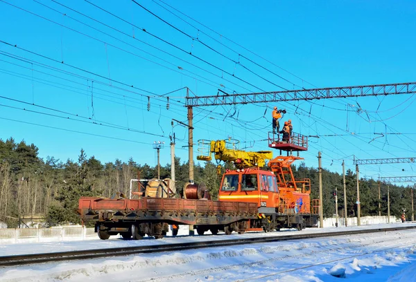 Special train with a landing crane for service and repair of electrical networks on the railway. Workers doing service work on electric lines over the rails