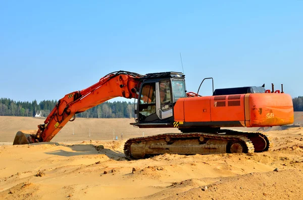 Excavator on the top of an open industrial sand pit where mining operations are carried out