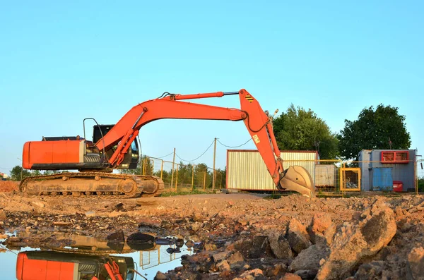 Excavator digs the ground for the foundation and construction of a new building. Road repair, asphalt replacement, renovating a section of a highway, laying or replacement of underground sewer pipes