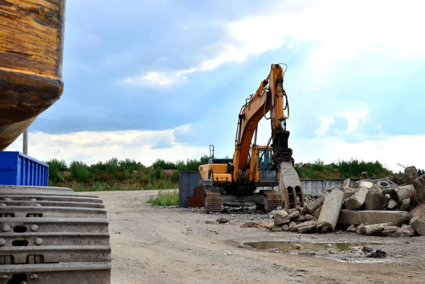 Industrial landfill for the processing of old, old concrete structures. Excavator with hydraulic demolition shears for crushing and cutting reinforced concrete slabs. Secondary crushed stone - Image