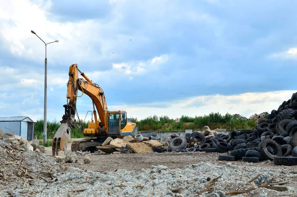 Industrial landfill for recycling used rubber tires and old concrete structures. Excavator with hydraulic shears for crushing and cutting reinforced concrete slabs. Secondary crushed stone - Image