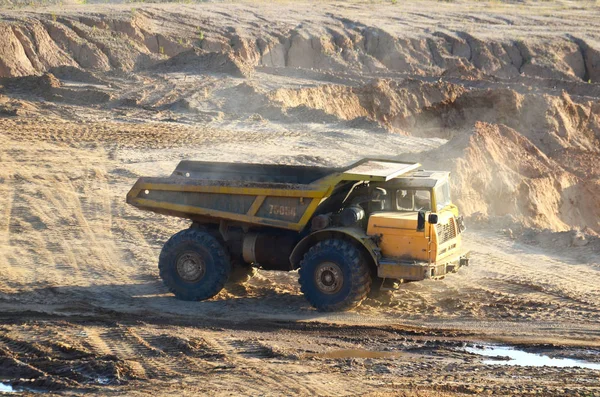 Big yellow dump truck works in an sand open-pit. Mining quarry for the production of crushed stone, sand and gravel for use in the construction industry - image