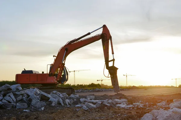 Crawler excavator with hydraulic hammer for the destruction of concrete and hard rock at the construction site. Replacing a concrete runway or road surface at an airport. Roadworks background