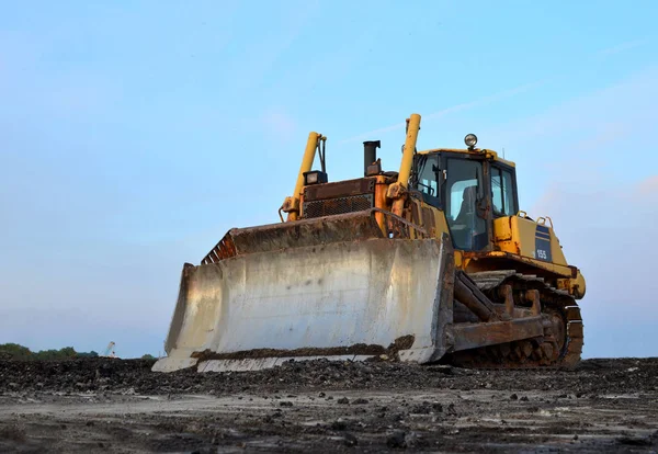 Track-type bulldozer, earth-moving equipment. Land clearing, grading, pool excavation, utility trenching, utility trenching and foundation digging during of large construction jobs.