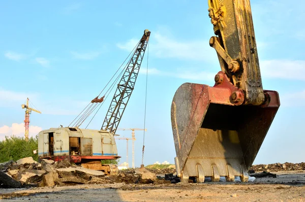 Excavator bucket on the construction site at sunset background and of the blue sky. Land Clearing, grading, pool excavation, utility trenching, utility trenching and foundation digging during